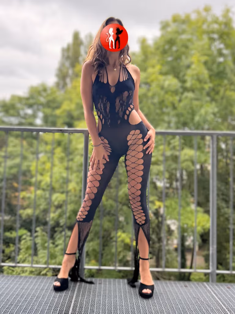 Vivienne steht im schwarzen Body auf einem Balkon